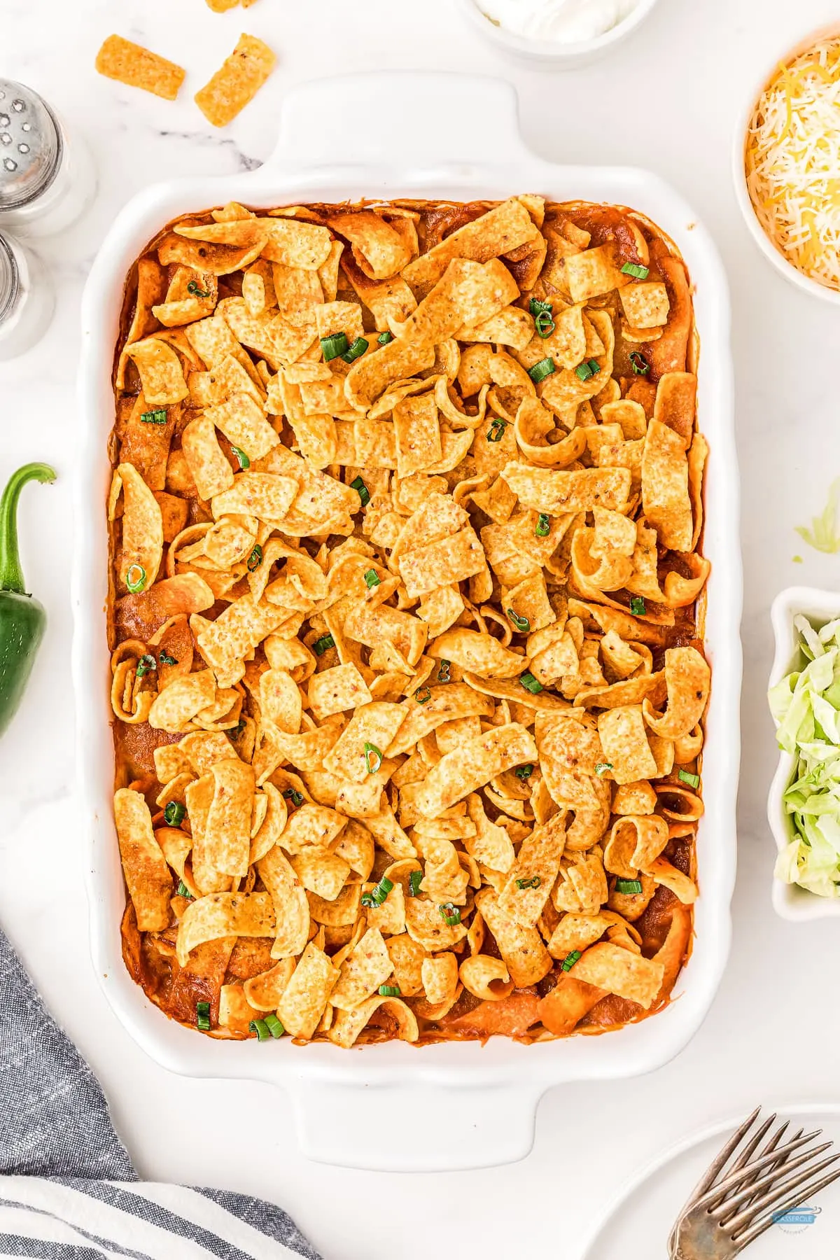 baked frito pie casserole in a white casserole dish with shredded lettuce
