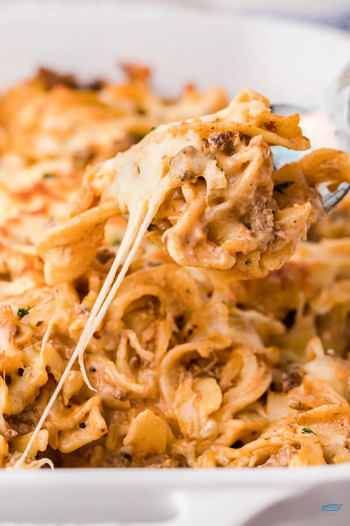 fork full of beef and egg noodle casserole with melted cheese