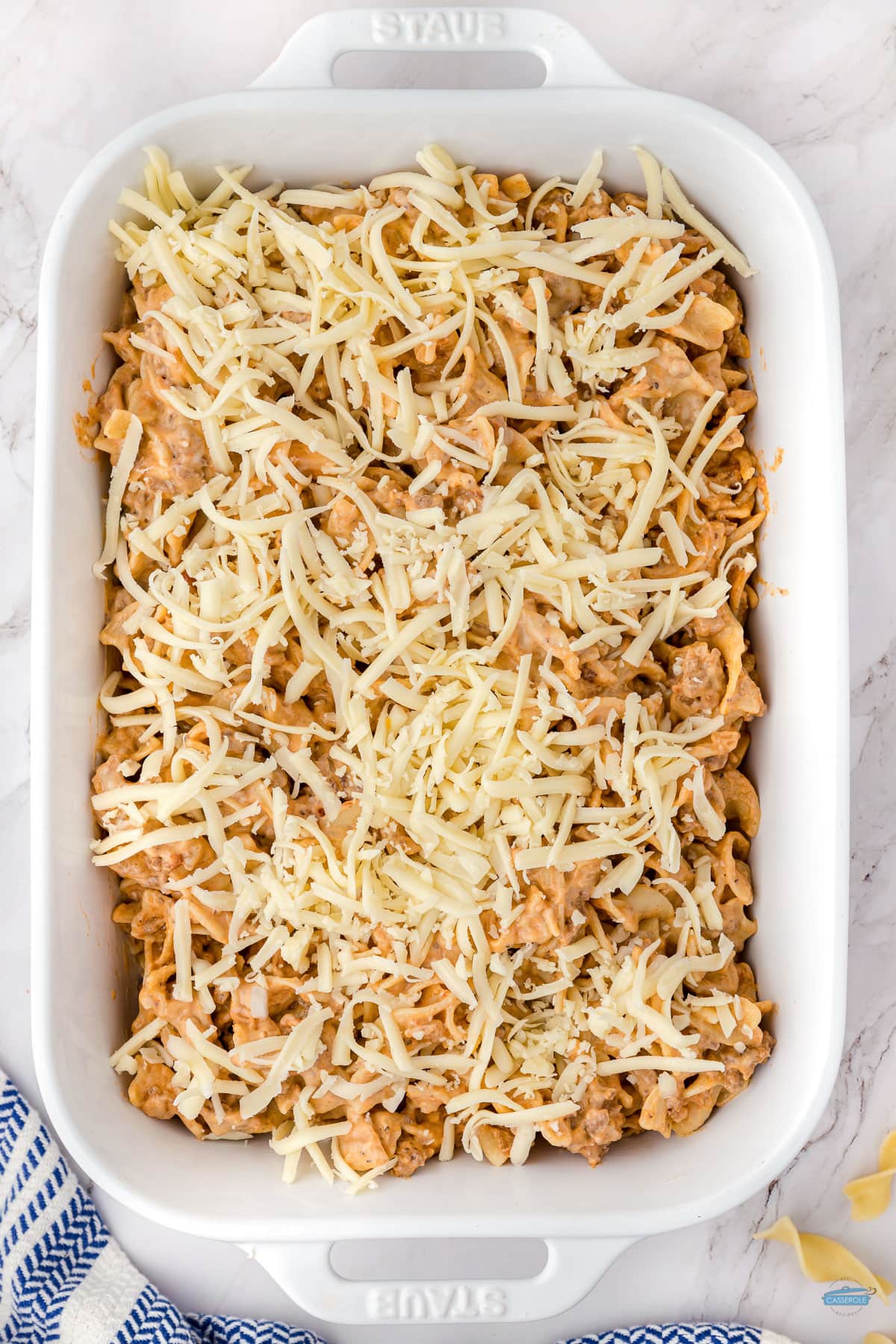 beef noodle casserole with cheese on top and unbaked