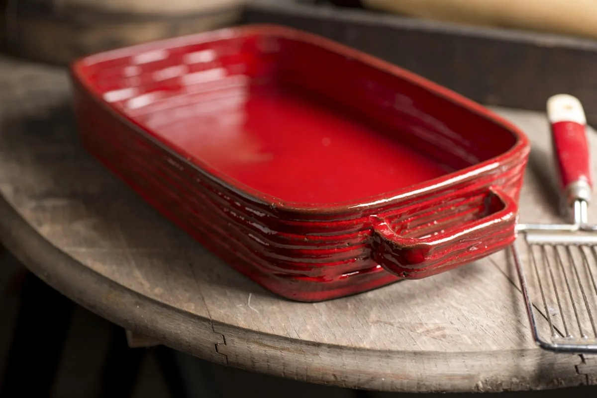 red baking dish on a marble table next to a spatula