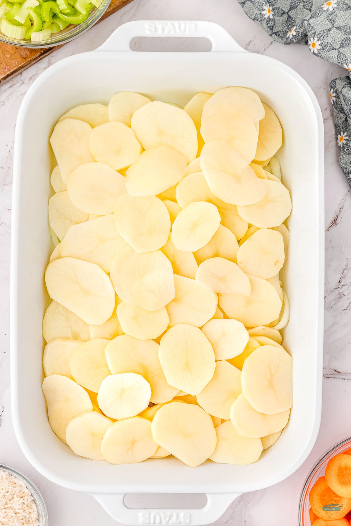 sliced onions and potatoes in a basserole dish