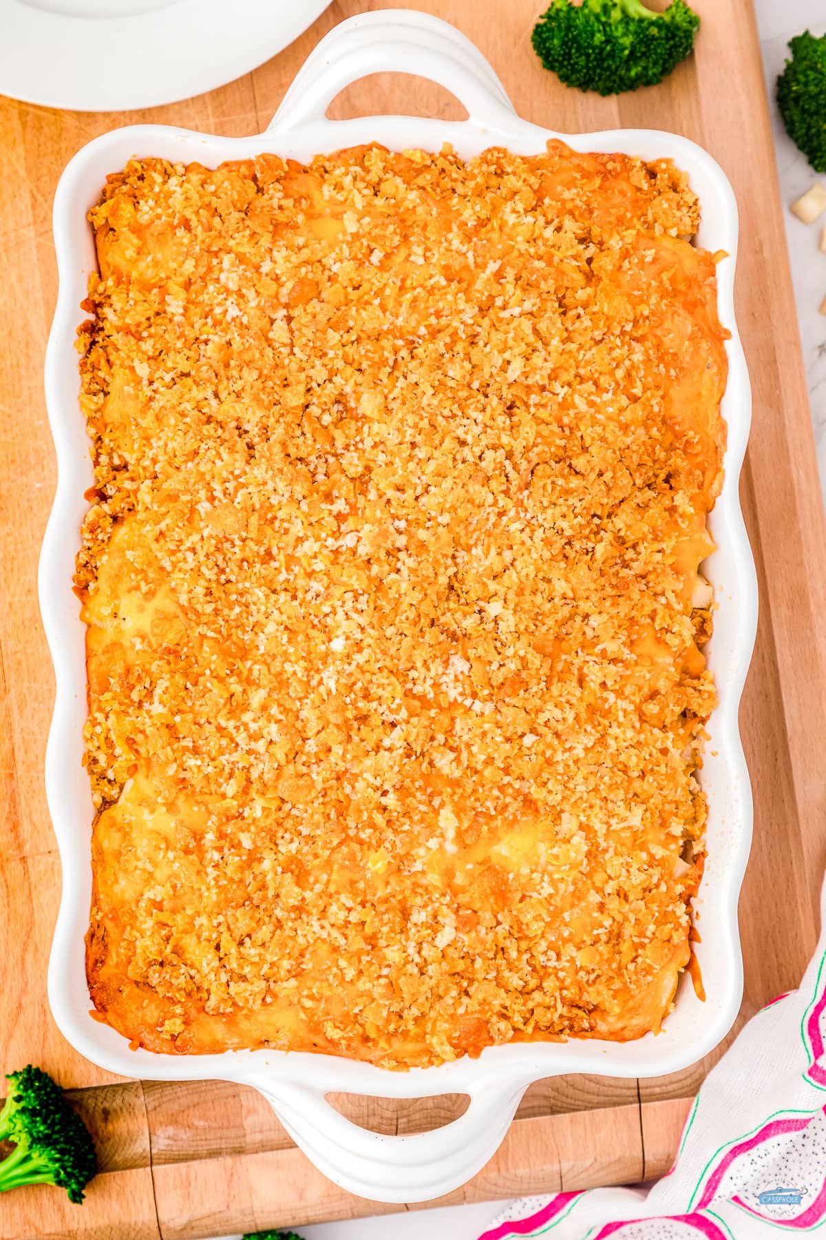 baked casserole in a white dish on a wood cutting board