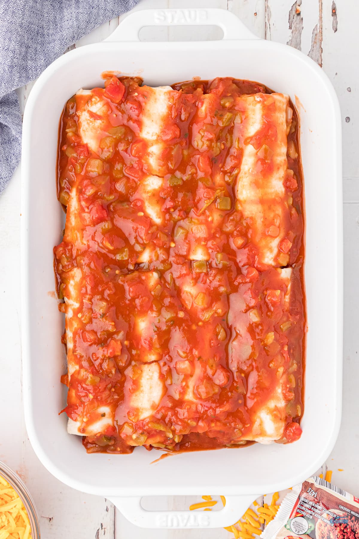 burritos covered in red sauce in a white casserole dish