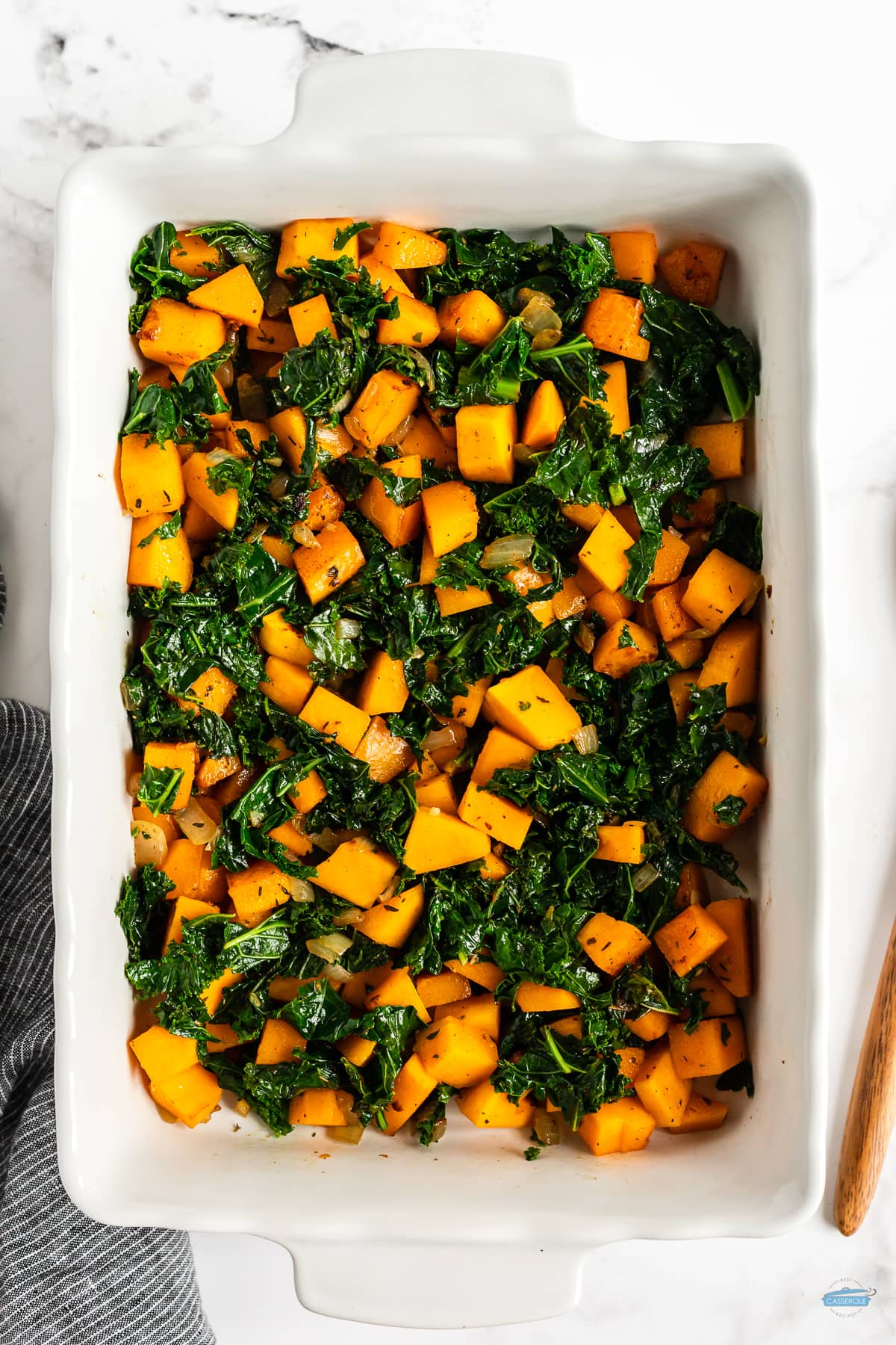 kale and squash in a white rectangle casserole dish