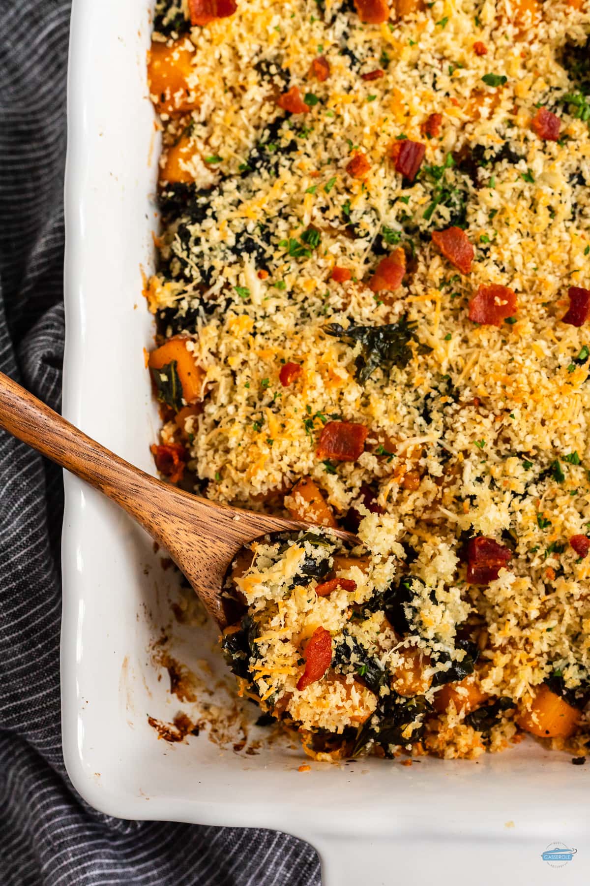 overhead picture of butternut squash casserole with a wood spoon