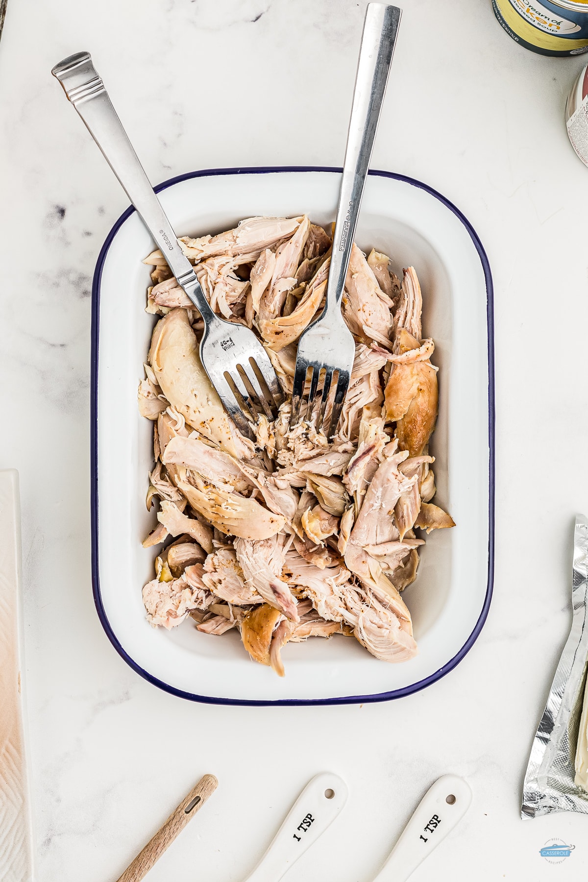 shredded chicken in a blue and whit4e dish with two forks