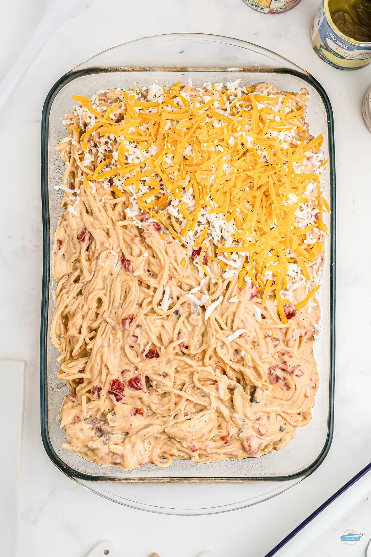 chicken spaghetti casserole in a clear dish half topped with cheese