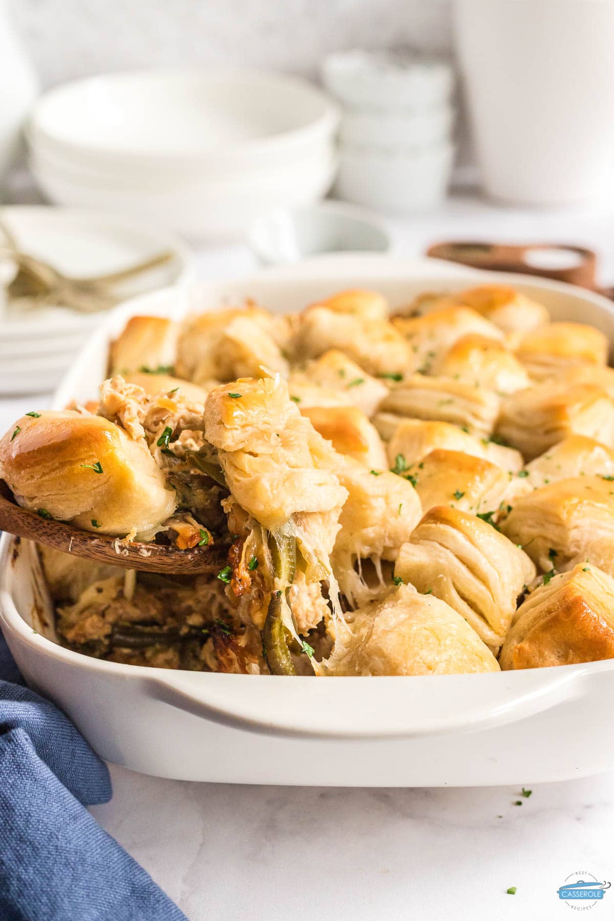 wood spoon scooping out  french onion chicken casserole topped with biscuits