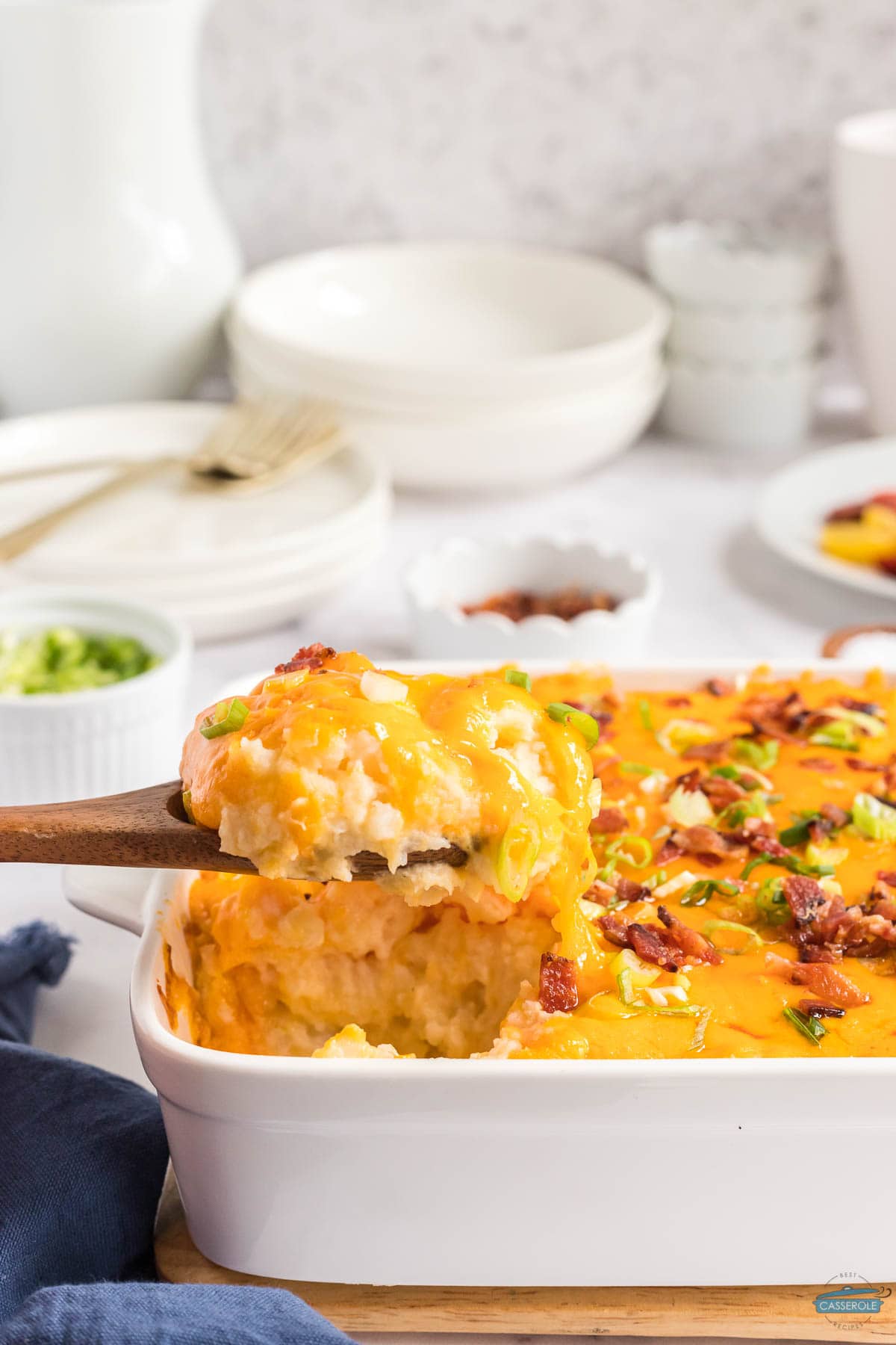 wood spoon scooping out twice baked potato casserole from a white dish