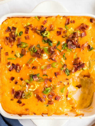 baked potato casserole in a white dish with a scoop missing