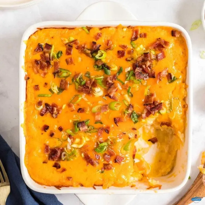 baked potato casserole in a white dish with a scoop missing