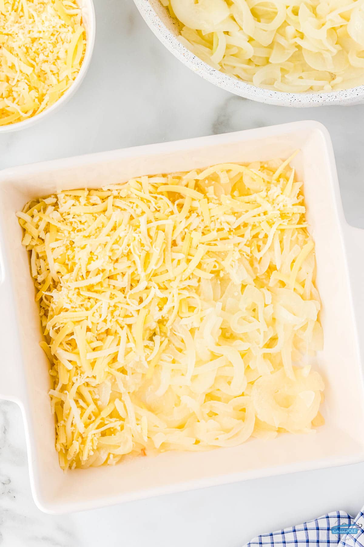 layers of onions and cheese in a white casserole dish