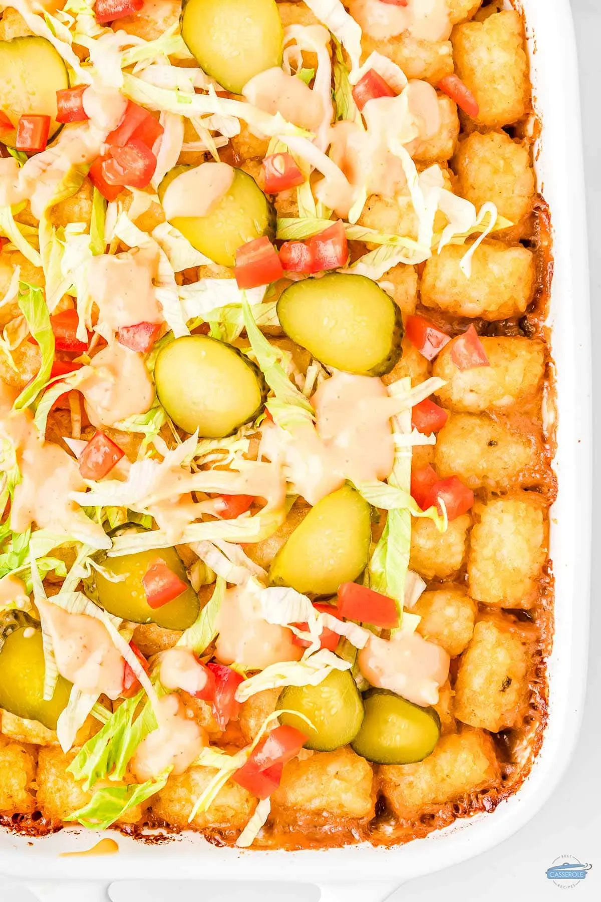 big mac tater tot casserole topped with lettuce and pickles