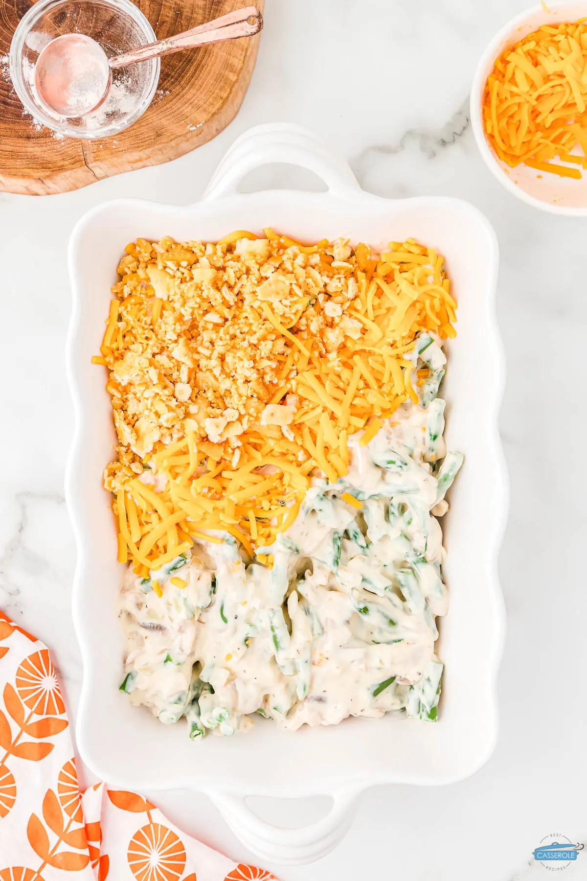green bean casserole in a rectangle dish half covered with crackers and cheese