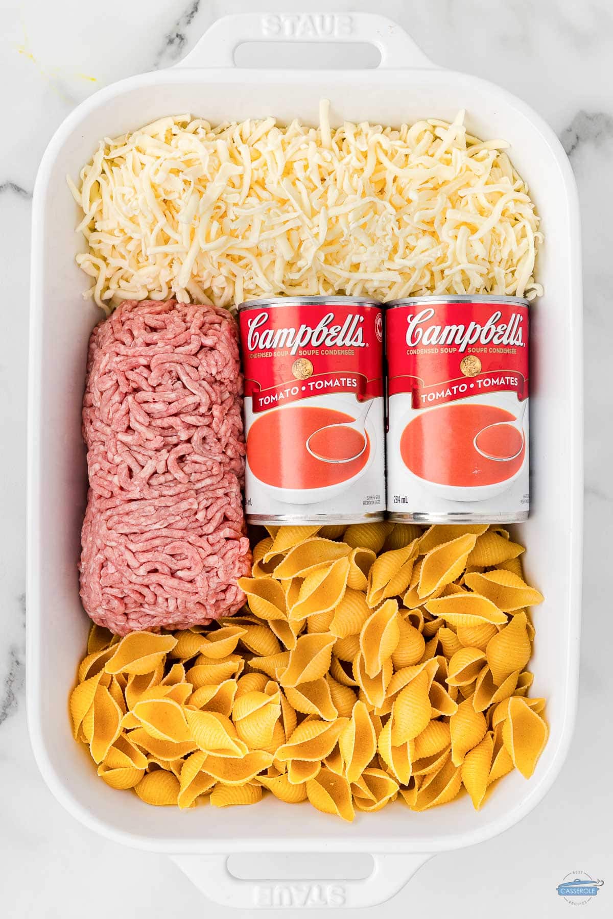 soup cans, pasta noodles, and ground beef in a rectangle casserole dish