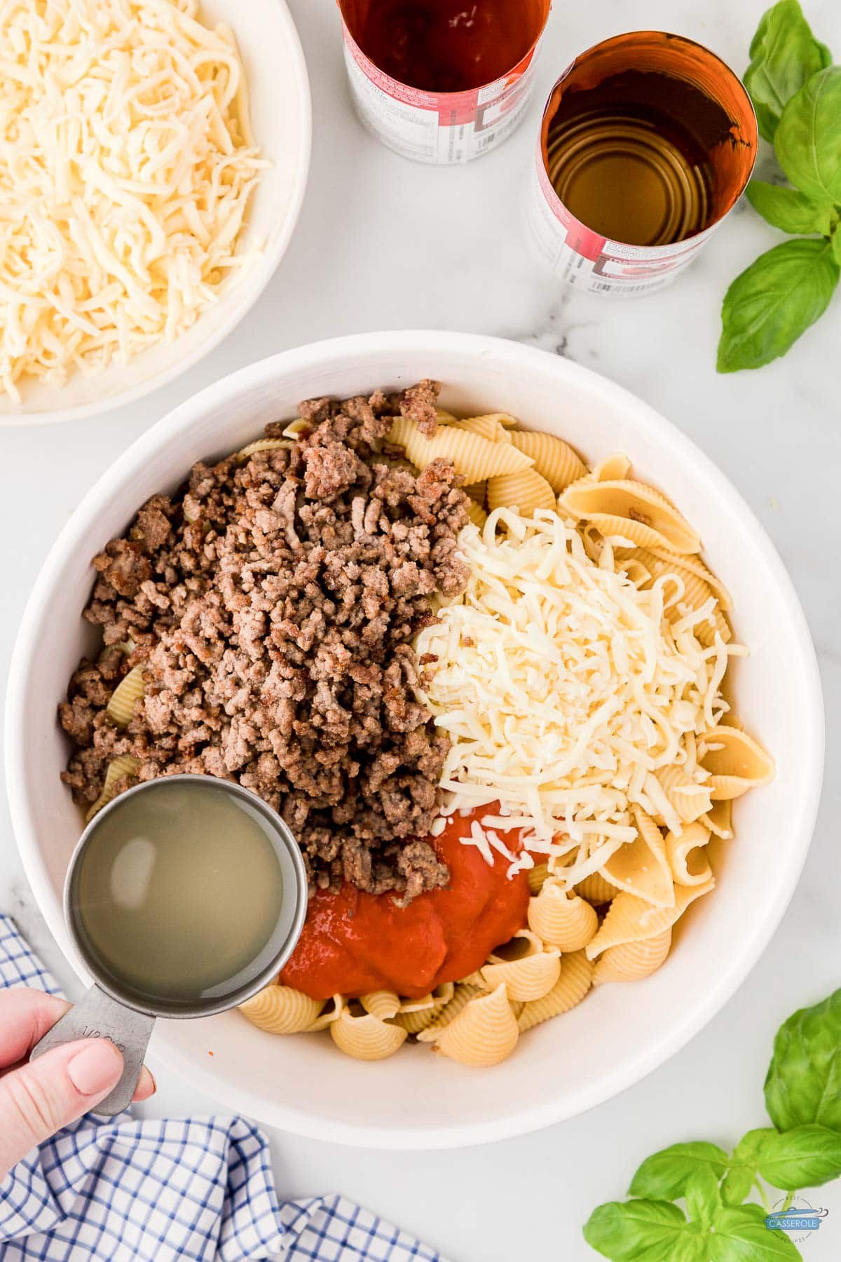 beef, cheese, tomato soup, and pasta shells in a white bowl