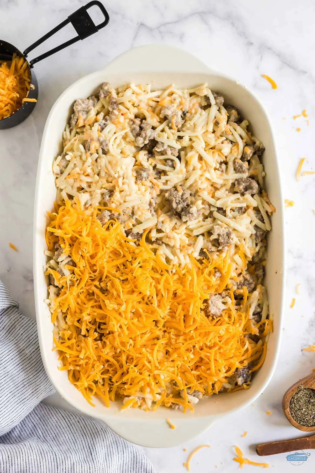 sausage casserole in a dish half covered with shredded cheese