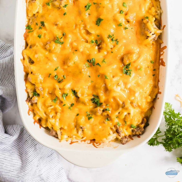 overhead picture of sausage casserole in a white dish with a blue and white striped napkin