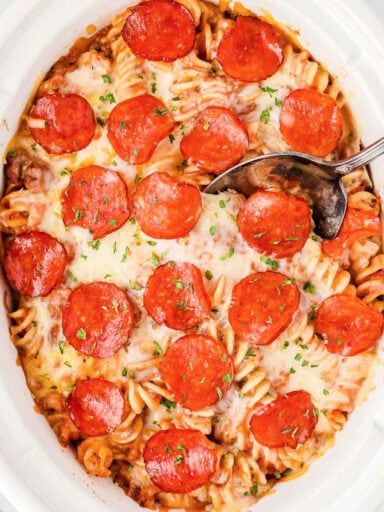 overhead picture of crockpot pizza casserole with a spoon in it