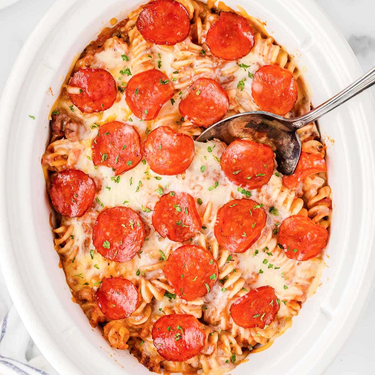 overhead picture of crockpot pizza casserole with a spoon in it