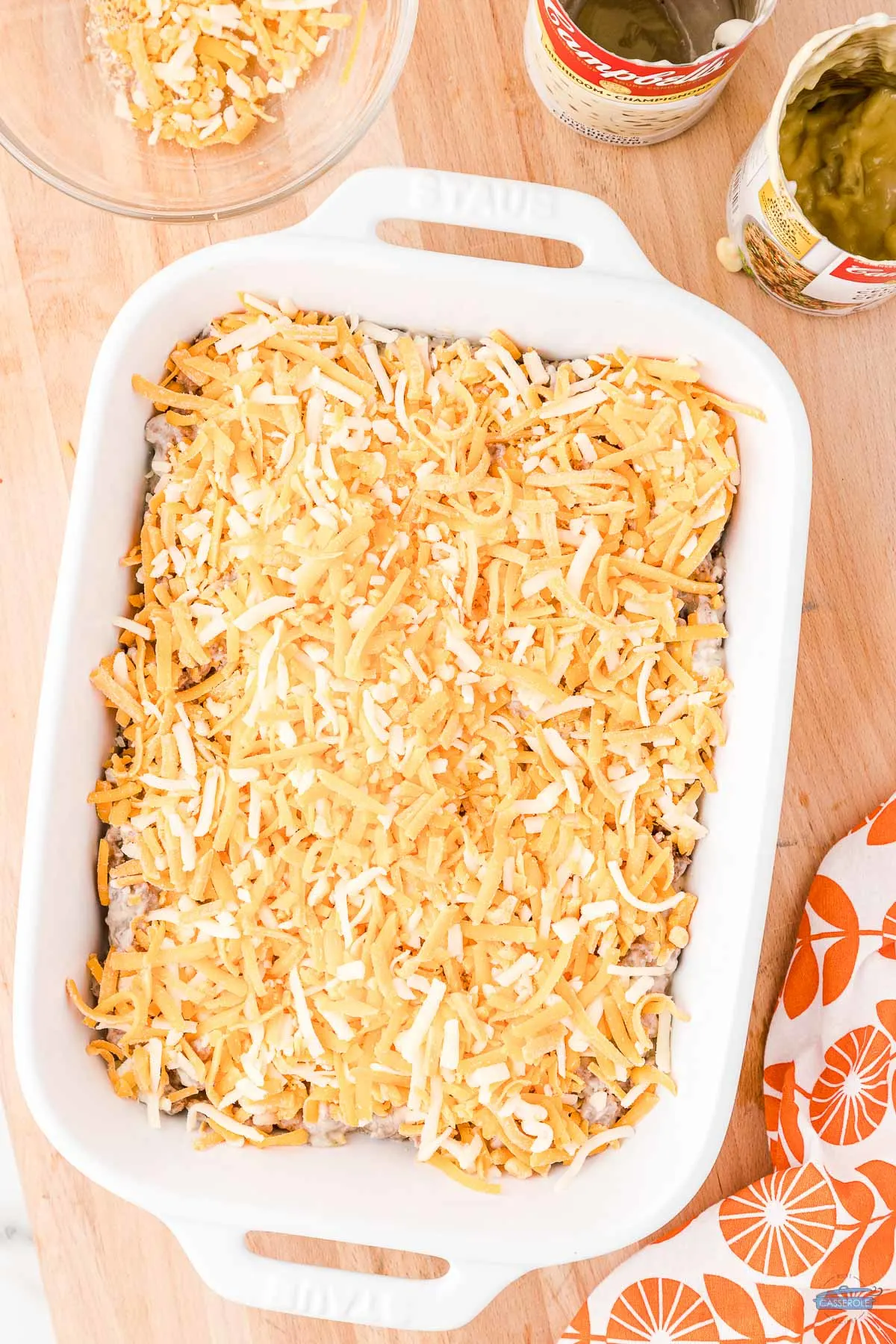 shredded cheese on a casserole in a white dish uncooked