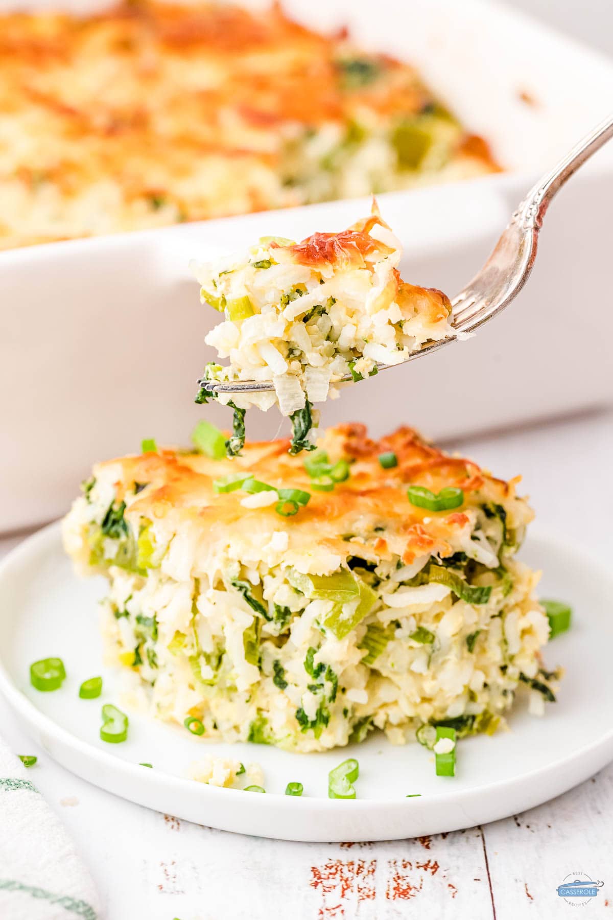 fork of green rice casserole on a plate