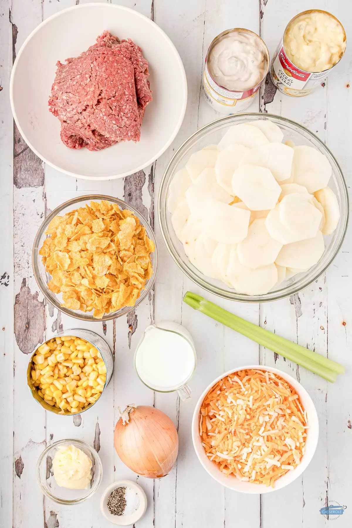 ingredients for hamburger potato casserole in individual bowls on a wood board