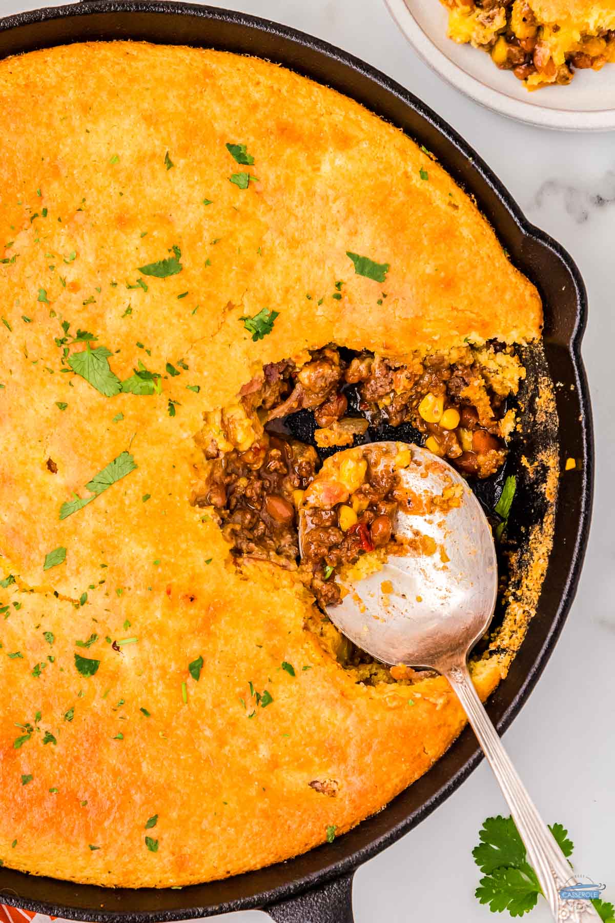 spoon scooping out cornbread cowboy casserole from a skillet