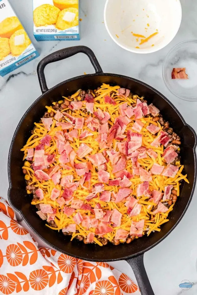 crumbled bacon on top of cheese in a skillet