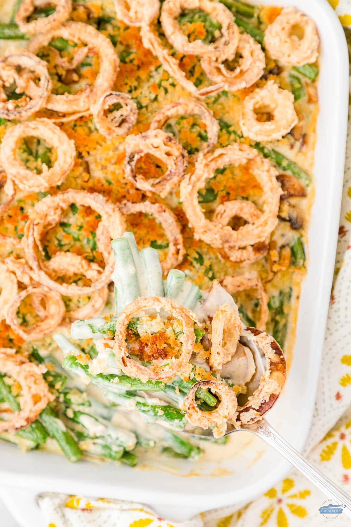 overhead picture of green bean casserole topped with onion rings in a white dish