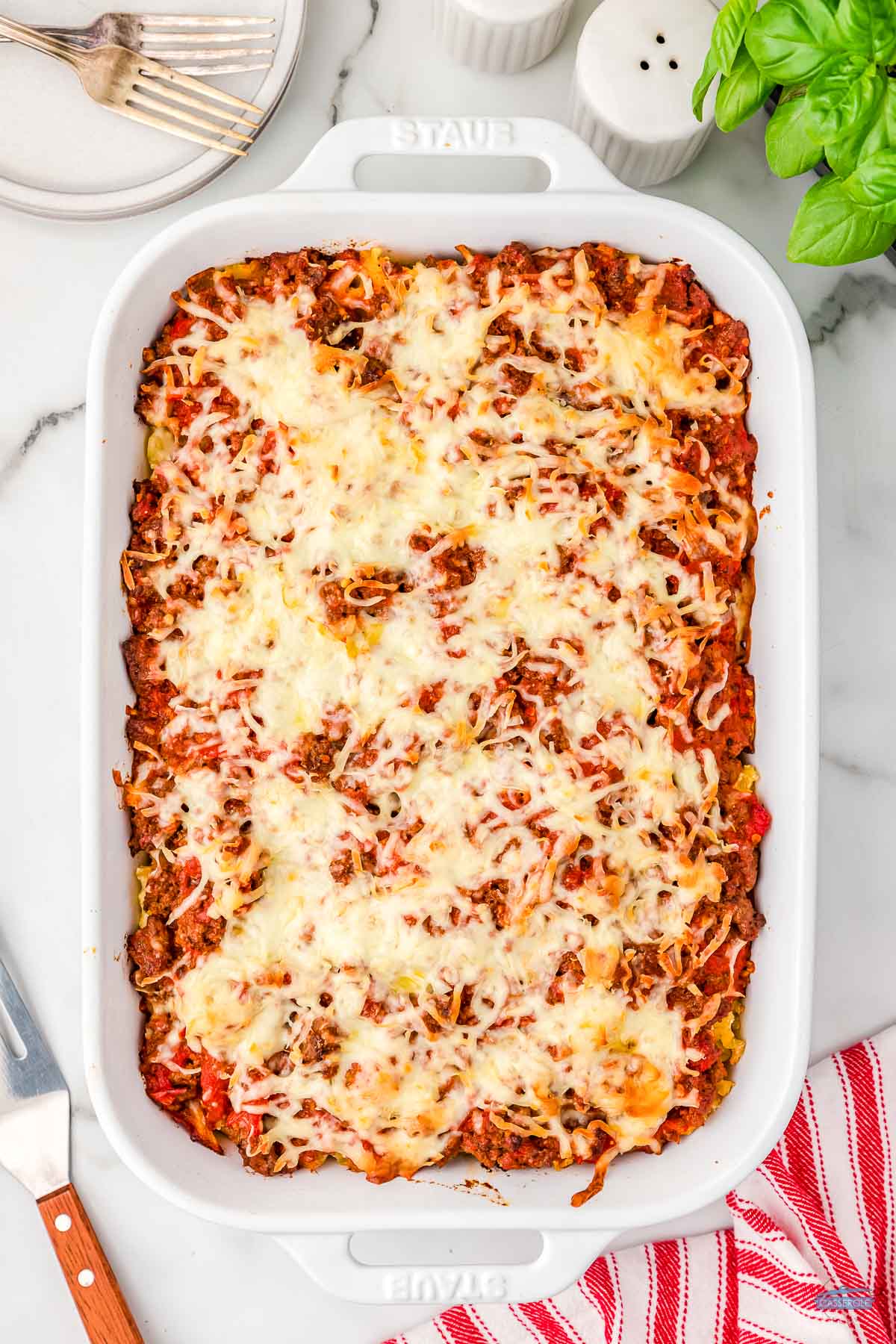 baked pasta casserole in a white dish with a red and white striped napkin