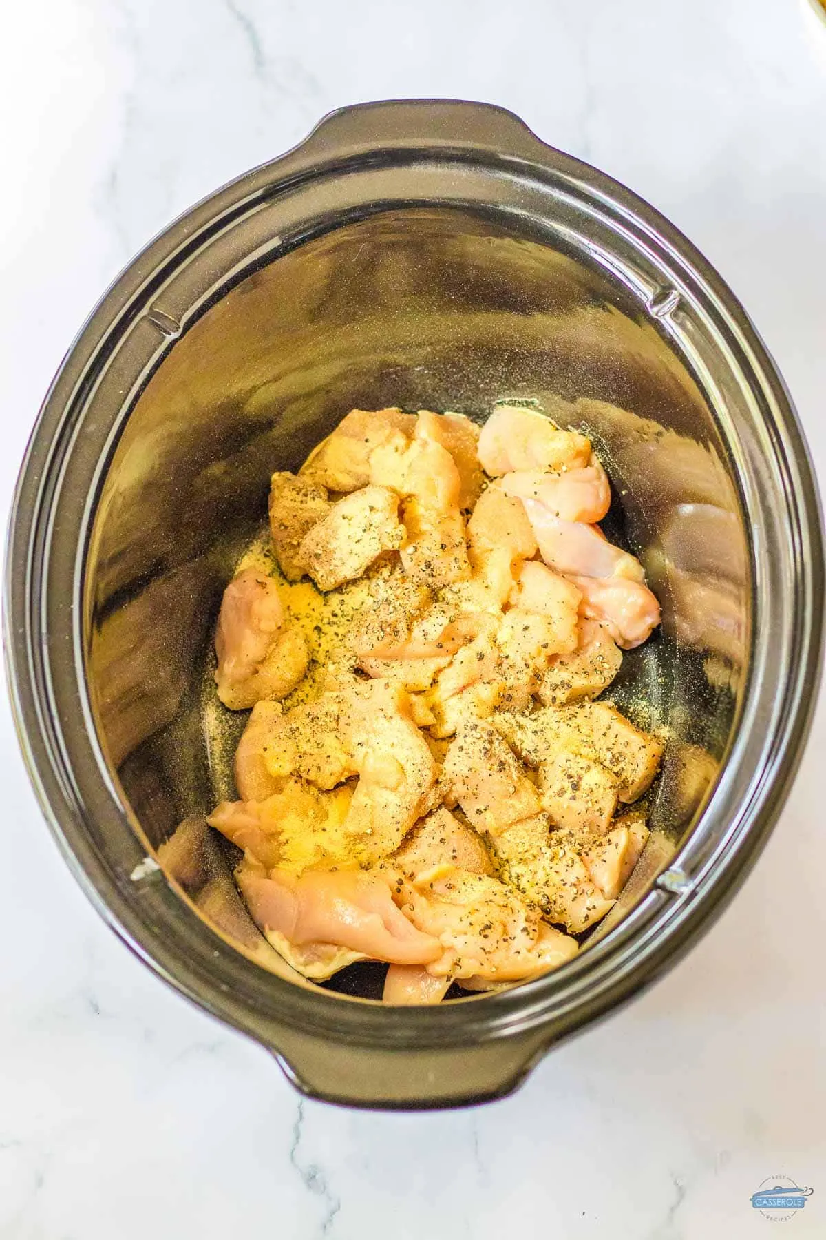 diced chicken and spices in a slow cooker bowl