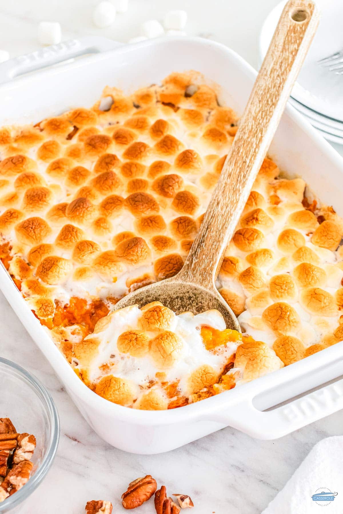 sweet potato casserole in a white dish with a wood spoon